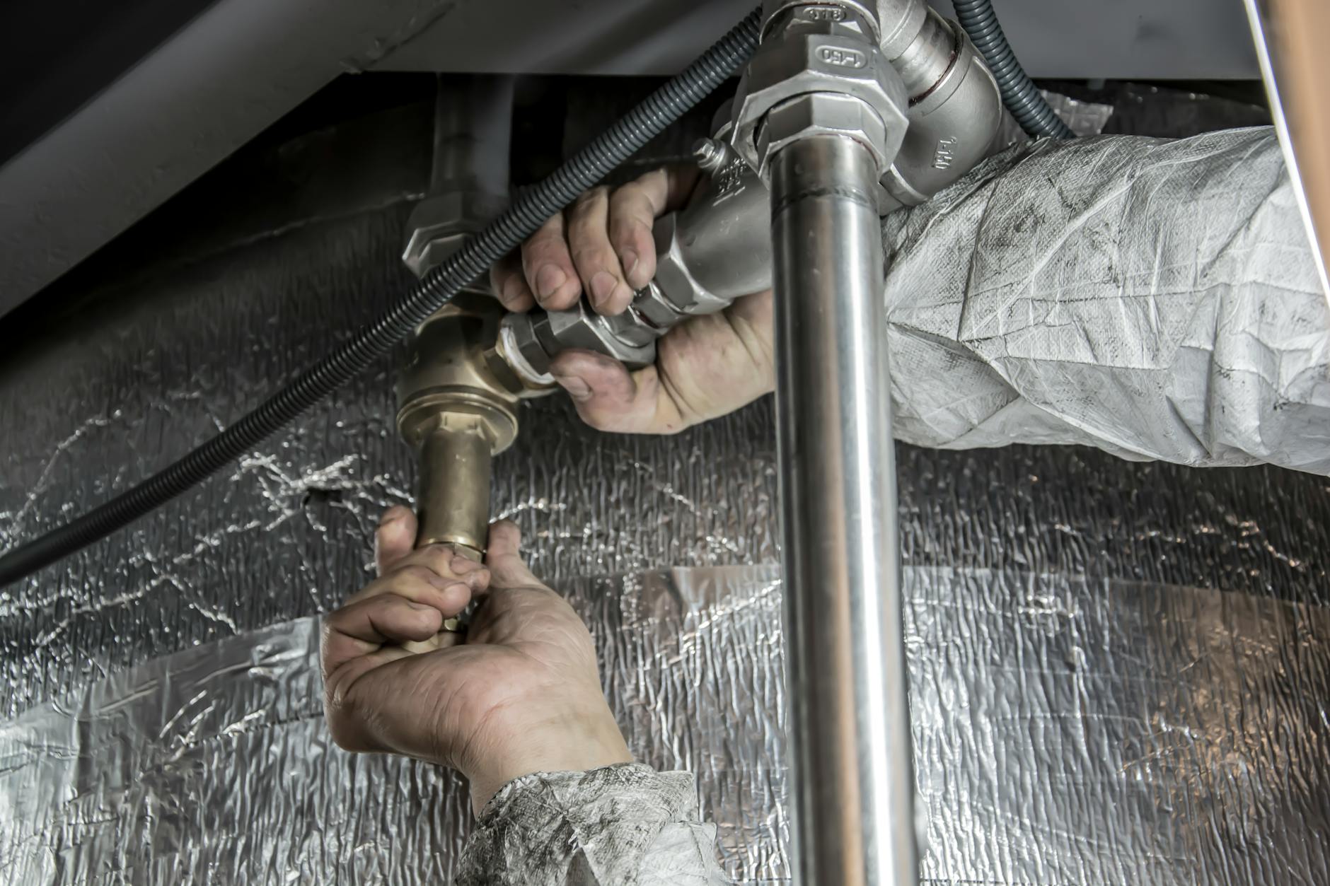 Ręce hydraulika montujące stalowe rury podczas remontu wnętrza